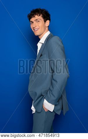 Positive Model In Suit And Shite Shirt Looking At Camera On Blue Background.