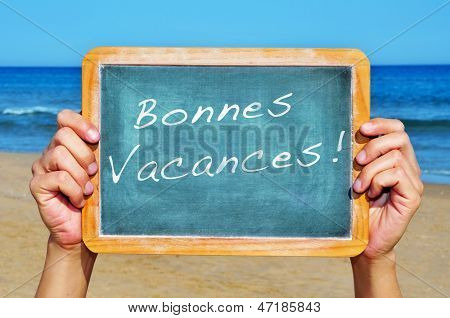 birisi cümle bonnes vacances, mutlu tatil içinde fren ile sahilde bir blackboard holding