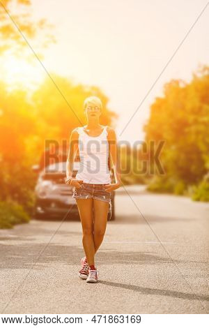Young Sad Woman Standing Near The Road By The Broken Car In The Middle Of Nowhere. Smoke Coming Out