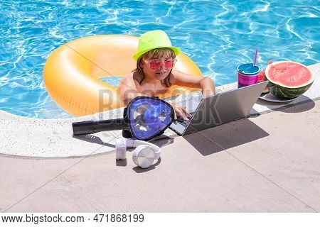 Child Relaxing In The Pool With Laptop. Kid Online Working On Laptop, Swimming In A Sunny Turquoise 