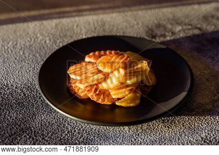 Delicious Crispy Fried Potatoes In Slices On A Black Ceramic Plate
