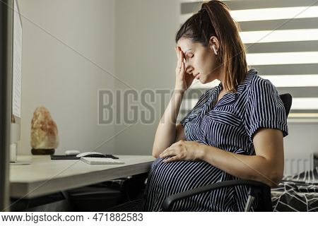 Home Office And Tired Pregnant Businesswoman. A Woman With A Huge Stomach Sits In Front Of A Compute