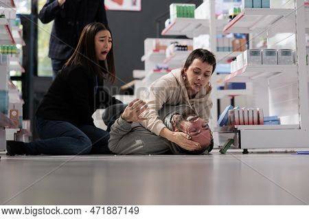 Women Crying And Screaming For Help During Person Epileptic Seizure In Medical Shop. Young Man Falli