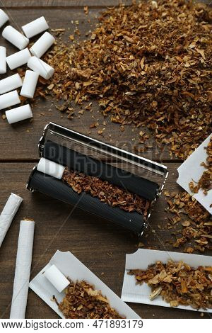 Flat Lay Composition With Roller And Tobacco On Wooden Table. Making Hand Rolled Cigarettes