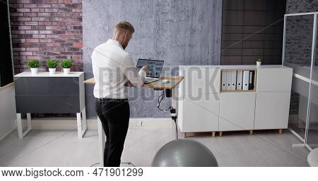 Man Using Adjustable Height Standing Desk In Office For Good Posture