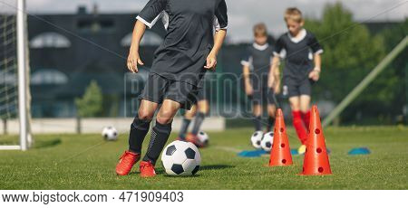 Group Of School Kids At Soccer Training. Boys Kicking Classic Black And White Soccer Balls In Slalom