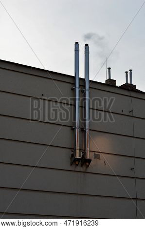 Industrial White Building With Sheet Metal Facade Of Repeating Rectangle Paneling. On Wall Are Two S