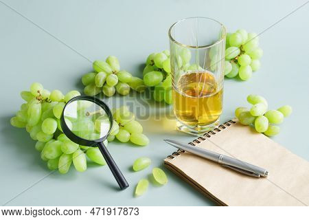 Grapes, Magnifier, Glass Of Grape Juice And Notebook With Pen On Light Green Background. Fruit Quali