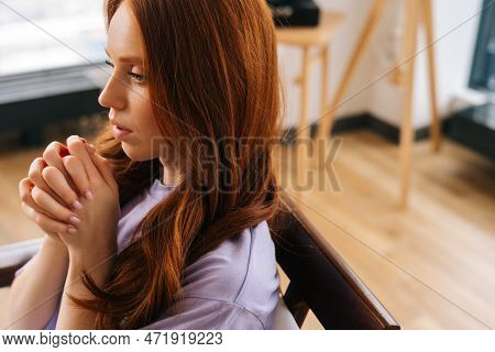 Close-up Face Of Despaired Young Woman Sincerely Praying Holding Folded Hands In Front Of Face At Ho