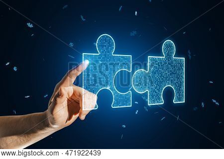 Close Up Of Businessman Hand Pointing At Glowing Digital Blue Jigsaw Puzzle Hologram On Dark Blurry 