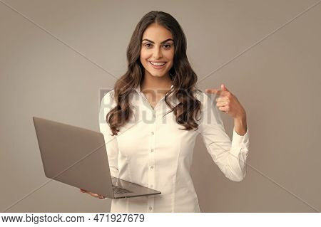 Portrait Of A Cheerful Young Casual Girl Standing Isolated Over Gray Background, Using Laptop Comput