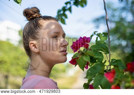 Portrait Of Happy Beautiful Girl, Young Positive Woman Is Smelling Beautiful Yellow Flowers In The G