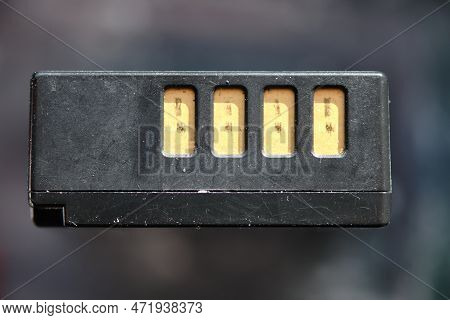 Close-up On Used Digital Li-ion Battery With Contacts. Isolated, Black On Blurred Background, For Cr