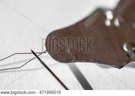 Sewing Needle Threader Tool In Use And A Single Black String.