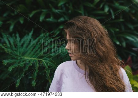 Portrait Of Young Woman Standing On An Ivy, Fern Wall Or In Greenery, Breathing, Smiling And Looking