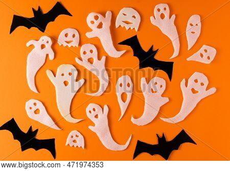 White Ghosts And Bat Craft For Halloween Party. Wrapping Paper Ghost On Orange Background Top View. 