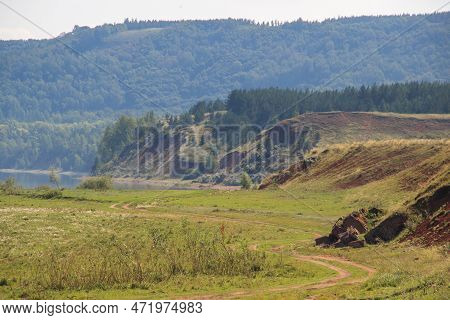Steep Red Clay Shores Of The Lake Covered With Coniferous Forest On A Hot Summer Day.