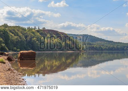 Lake Surrounded By Green Forest, Hill With Forest On Background.summer Day.large Rock In Water