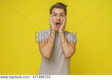 Shocked Young Man 20s With Hands On Cheecks And Open Mouth, Omg Sign. Excited Young Man Screaming, A