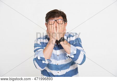 Man Dressed In Blue Shirt Covering His Face By Hands Isolated On White Background. Man No Tearing. S