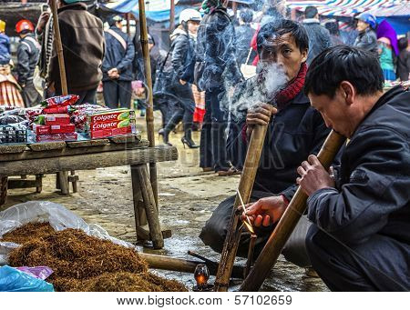 Lighting And Smoking Tobacco In Traditional Long Pipes At Sunday Market.