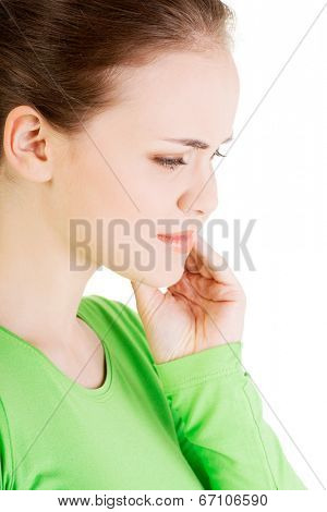 Teen woman pressing her bruised cheek with a painful expression as if she's having a terrible tooth ache.