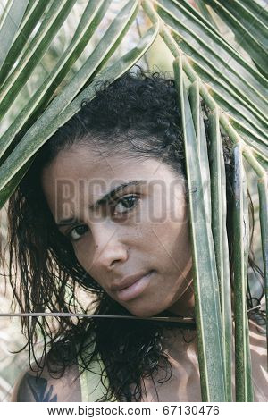 Beautiful Woman Looking Though Leaves during sunny day.