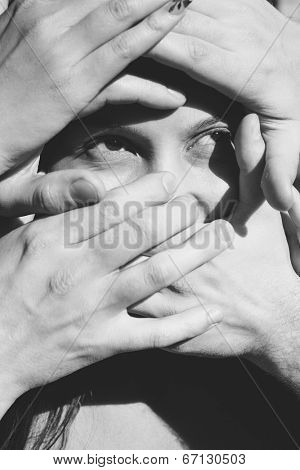 Black and White Photo of Woman with Face Covered by many hands.