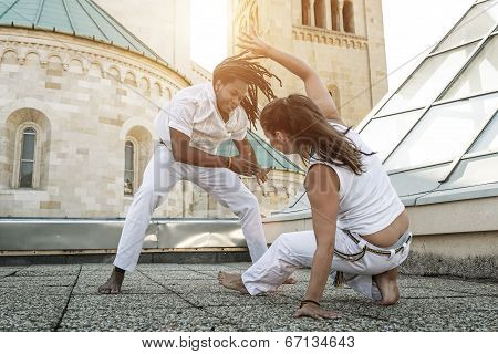 Young pair capoeira partners performing kicks outdoor