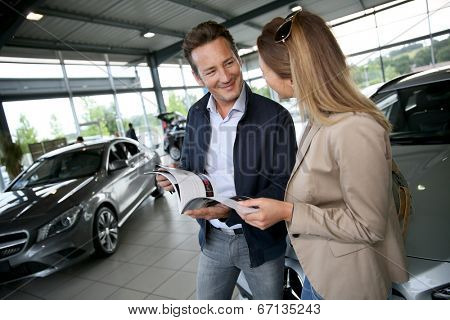 Couple looking at dealership brochure to choose vehicle