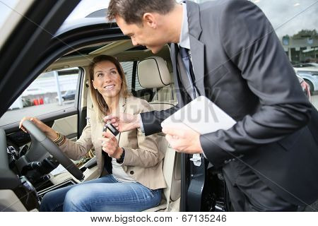 Car dealer giving key to new car owner