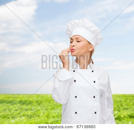 cooking, gesture and food concept - smiling female chef showing delicious gesture