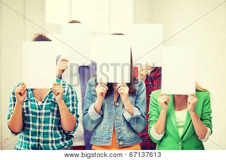 education concept - group of students covering faces with blank papers
