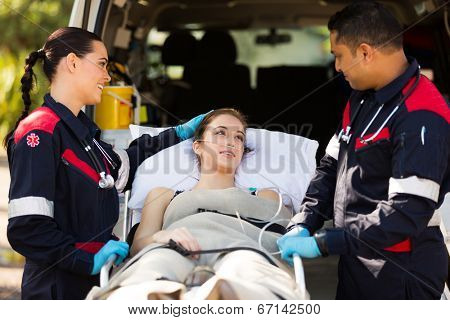 friendly paramedic comforting young patient before transporting her to hospital