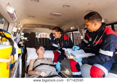 caring paramedics talking to patient on ambulance on the way to hospital