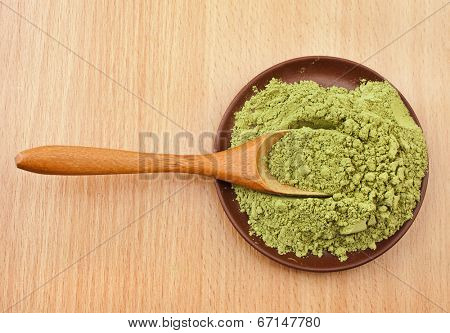 Powdered Green Tea Matcha in spoon on wood table surface  background