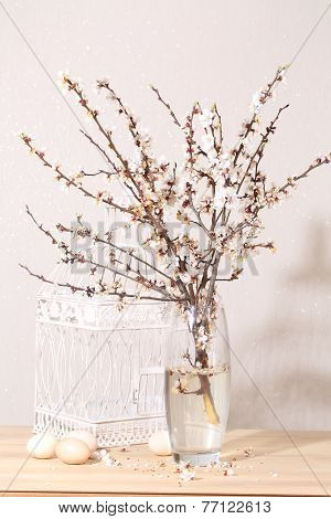 Easter still-life with a blossoming branch, eggs and a white cage