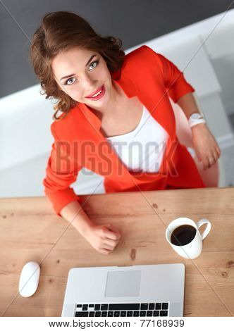 Attractive woman sitting at desk in office, working with laptop