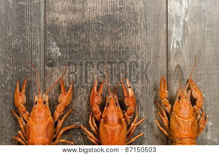 Three Red Crayfishes In A Row On Old Wooden Table Close-up