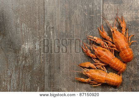 Three Red Crayfishes In The Left-bottom Corner On Old Wooden Table