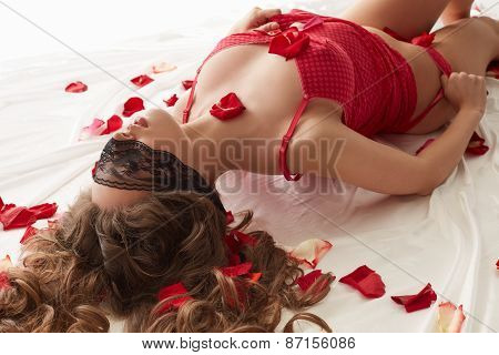 Excited woman with blindfold lying in bed