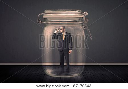Businessman trapped into a glass jar concept on background