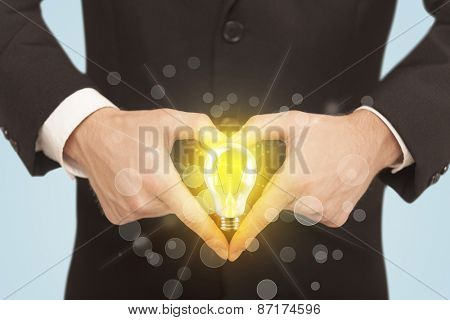 Hands creating a form with yellow light bulb in the center