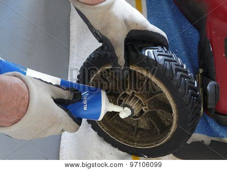 Man Greasing Lawn Mower Wheel