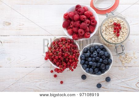 Breakfast - berries, fruit and muesli on white wooden