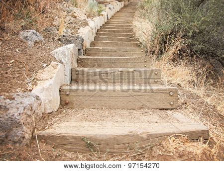 wooden steps going up a hill made out of stone and railroad tie blocks of wood