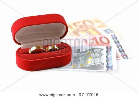 Wedding rings in box on banknotes, isolated on white background. Marriage of convenience