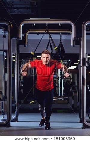 A man is doing exercises on  simulator in the gym.