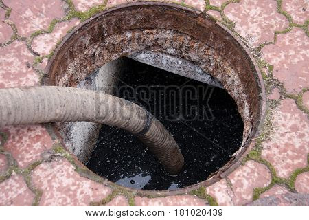 man pumping sewage from the drain hole.