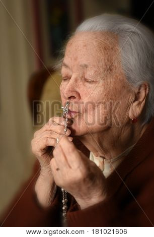 Old Woman Praying And  Holding Silver Rosary